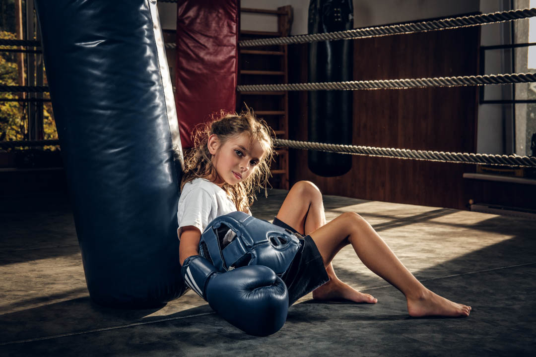 Little Tired Girl With Blue Helmet Is Resting Ring Punching Bag